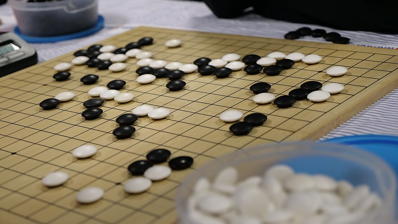 Black and white Go stones cover a wooden board at a tournament in Toulouse.