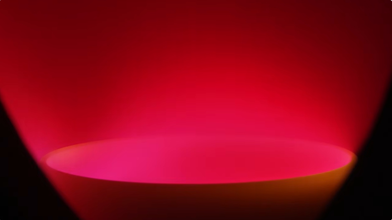 A lithium-fed electric thruster prototype emits a bright red plasma plume during a ground test