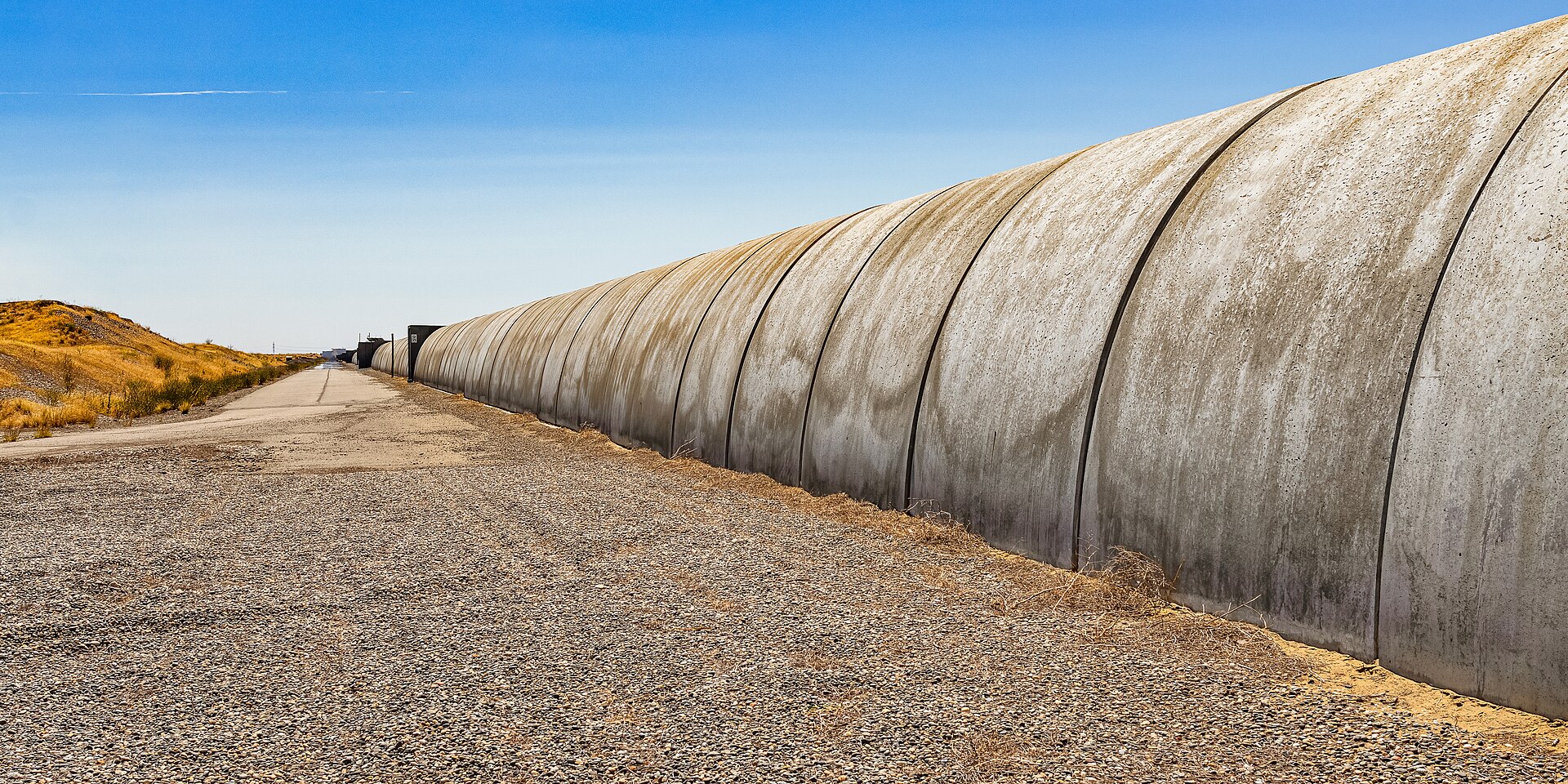 A long concrete-covered laser interferometer tube at LIGO Hanford in the dry Washington landscape.